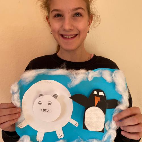 Mädchen zeigt selbst gemachtes Bild mit Eisbär und Pinguin